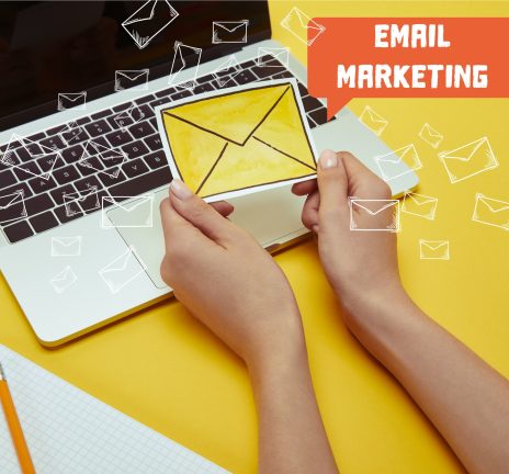 cropped image of woman holding envelope sign near laptop with"email marketing" lettering and email